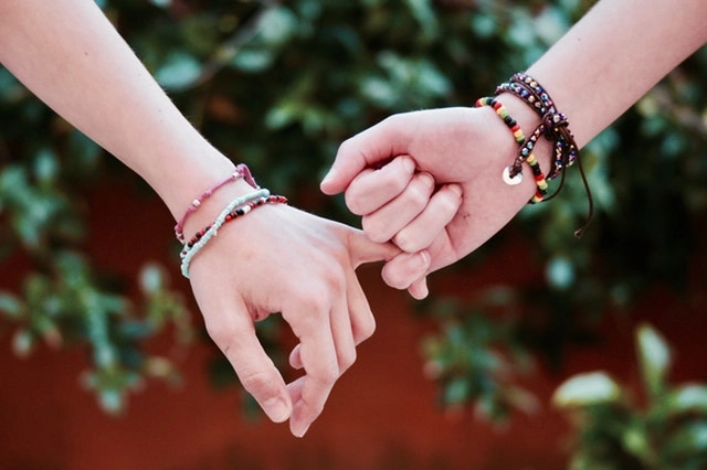 USCW-adult-beads-bracelets-holding-pinkies Adults holding pinkies with beaded bracelets.